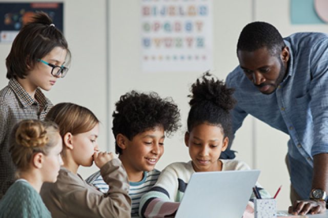 teacher with kids looking at laptop